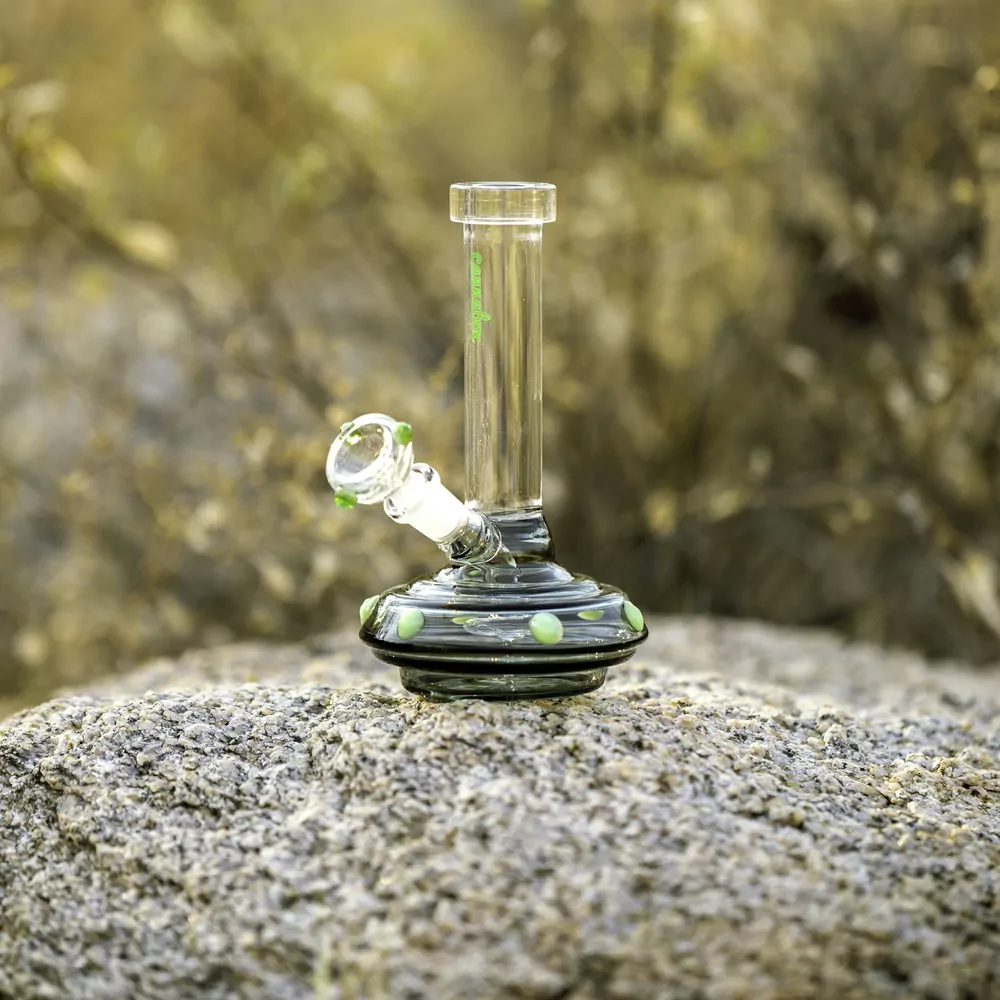A small clear glass water pipe standing on a rock