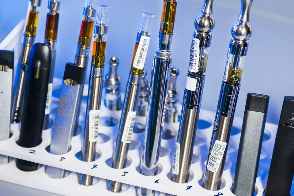Vape pens, batteries and cartridges lined up in a white display stand
