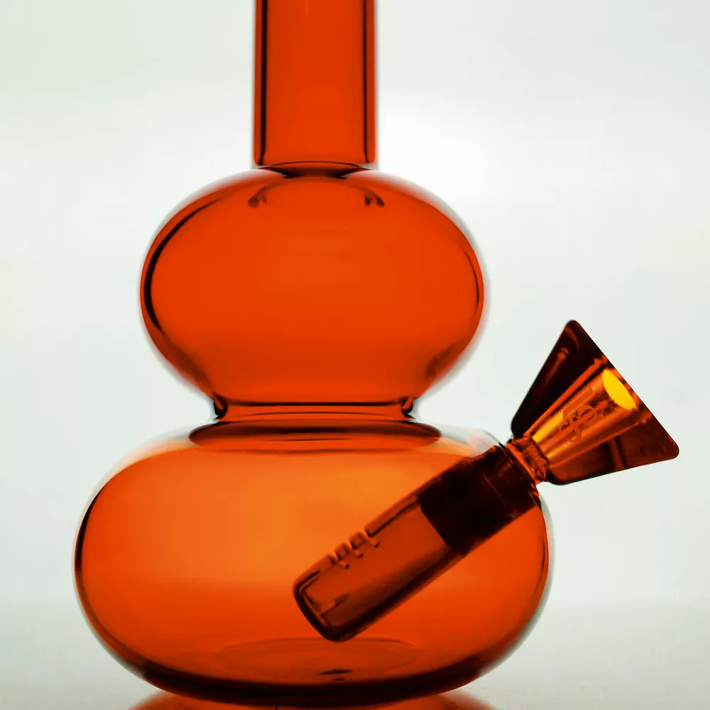 A small orange glass water pipe with a matching bowl, on a white background