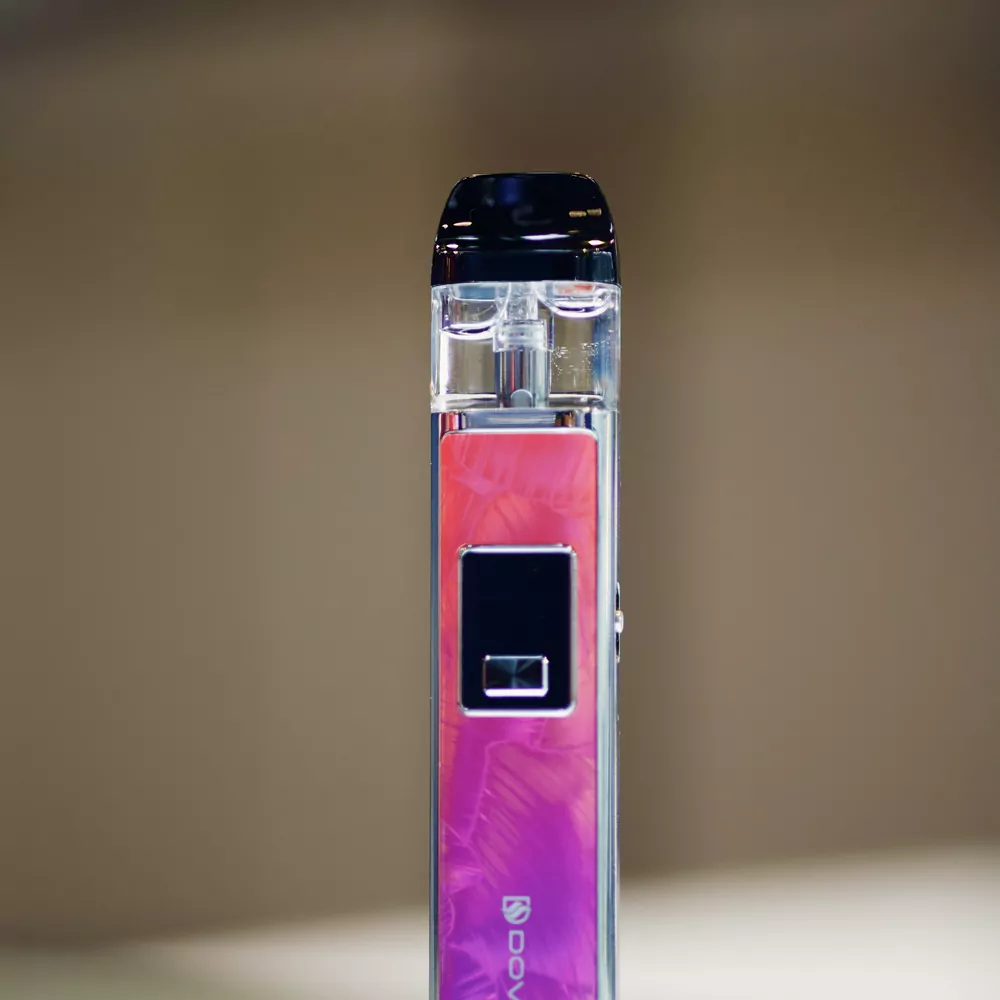 A pink pod system device with a clear pod, standing upright on a white table