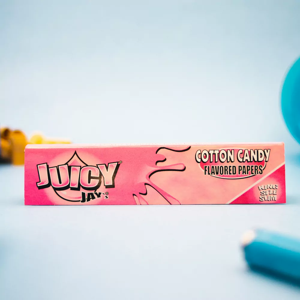 A pink pack of cotton candy flavoured rolling papers on a pale blue background