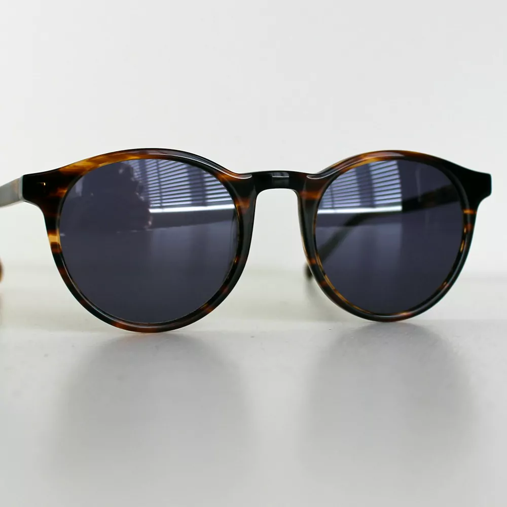 Round tortoiseshell sunglasses with dark lenses on a white table